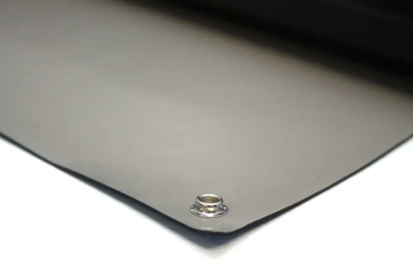A close-up of Conductive Rubber Bench Matting shows its smooth, dark surface with a metal eyelet in one corner, resting on a white background.
