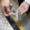 A person holds a piece of Anti-Slip Comfortable Tape above metal flooring featuring textured patterns and a yellow strip along the edge.