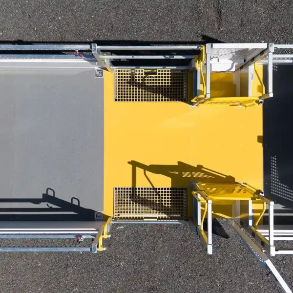 Aerial view of a yellow and grey Anti-Slip Flat Sheet with railings, gates, and grates on asphalt, designed for secure access or walkway use.