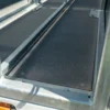 Close-up of a textured black Anti-Slip Flat Sheet secured with bolts inside a metal frame, likely part of a vehicle or equipment storage compartment.
