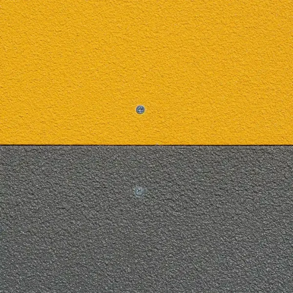 A wall is split horizontally into two equal sections of Anti-Slip Flat Sheet: the top half is textured yellow, the bottom half is textured grey, each with a single visible screw centred in its section.