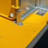 Close-up of a yellow Anti-Slip Flat Sheet and metal fittings in a vehicle, showing part of the door mechanism, pole, and base with bright colours and reflective surfaces.