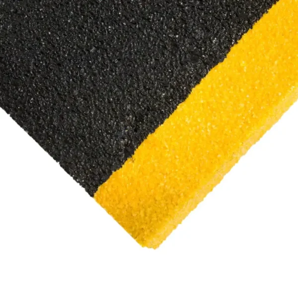 Close-up of the Anti-Slip Stair Tread’s textured surface, diagonally divided: black on the upper left and bright yellow on the lower right. The rough finish enhances grip for added stair safety.
