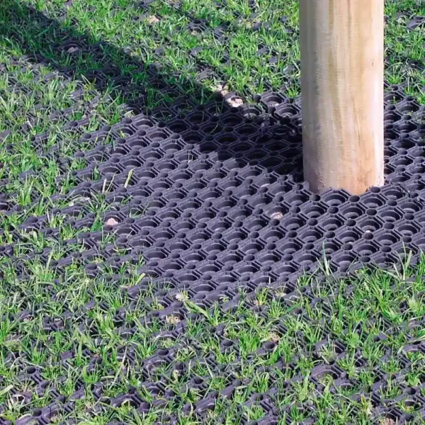 A wooden pole stands on a grassy surface protected by a 16mm Black Grass Mat, which shields the grass and ground around the base of the pole.